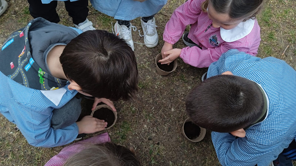 Bambini riempiono i vasetti di terra