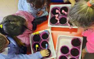 Bambini decorano i loro vasetti pieni di terra