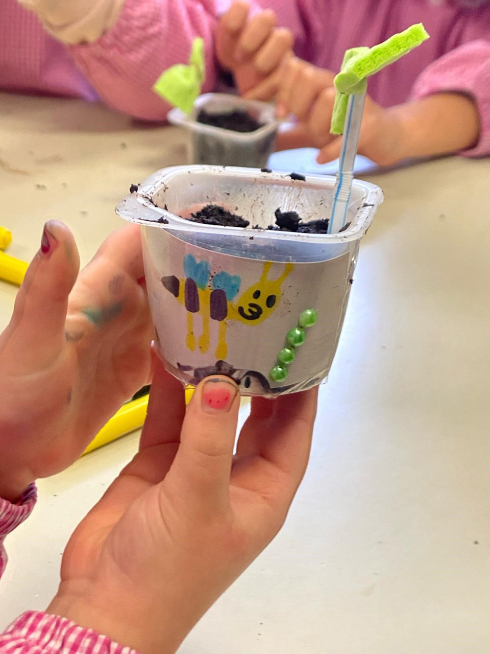 mano di bambino con un vasetto in cui c’è una piccola piantina mano di bambino con un vasetto in cui c'è una piccola piantina
