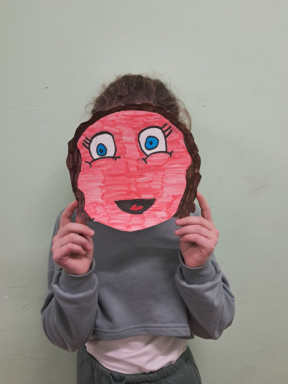 foto di bambino con volto coperto da disegno che rappresenta un emoticon