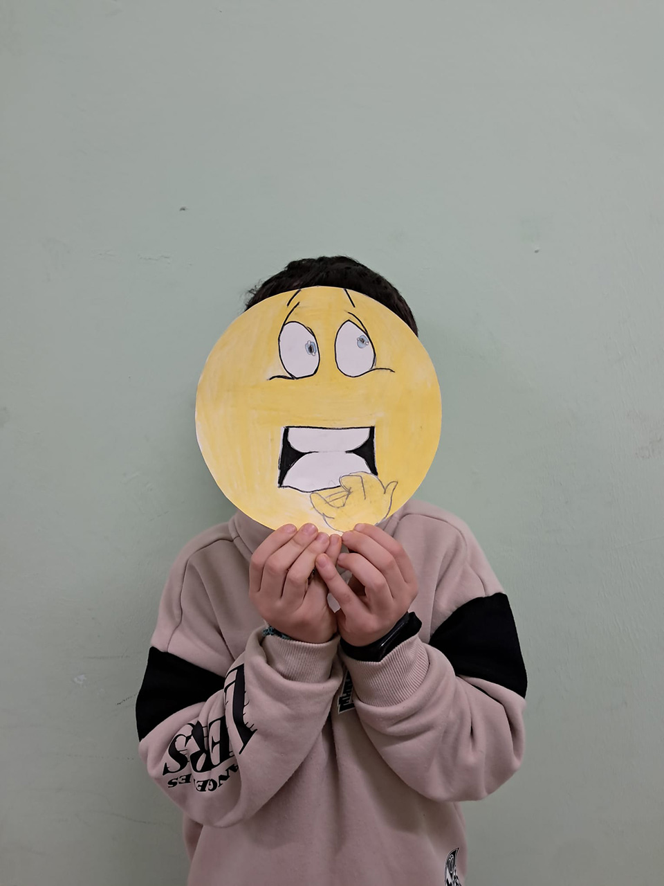 foto di bambino con volto coperto da disegno che rappresenta un emoticon