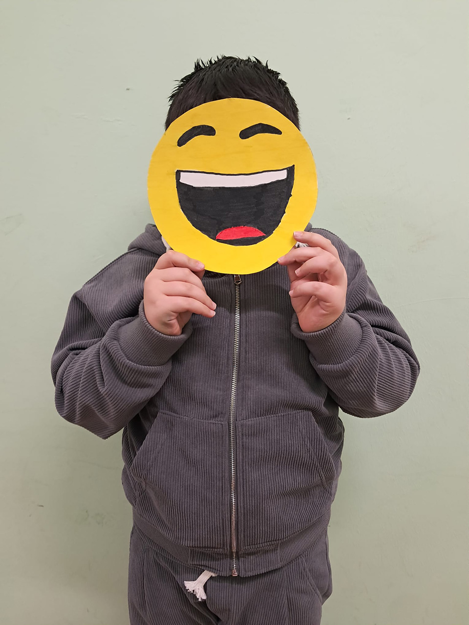 foto di bambino con volto coperto da disegno che rappresenta un emoticon