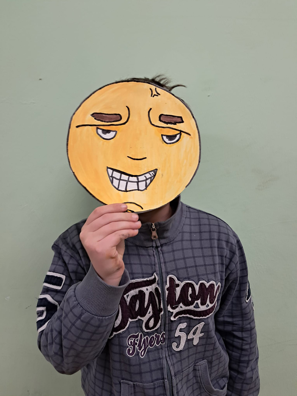foto di bambino con volto coperto da disegno che rappresenta un emoticon