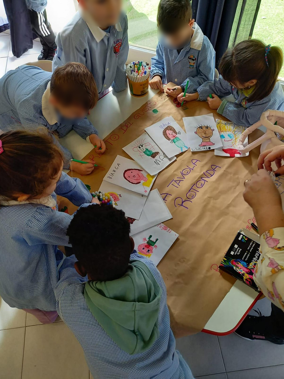 foto di bambini che creano un cartellone con disegni per progetto tavola rotonda