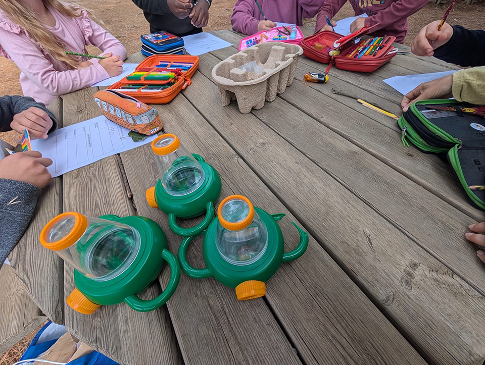 foto di bambini intorno a un tavolo con fogli, astucci