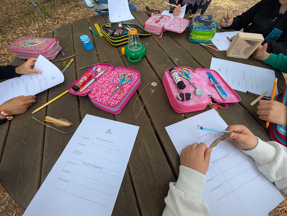 foto di bambini ntorno a un tavolo con fogli e astucci