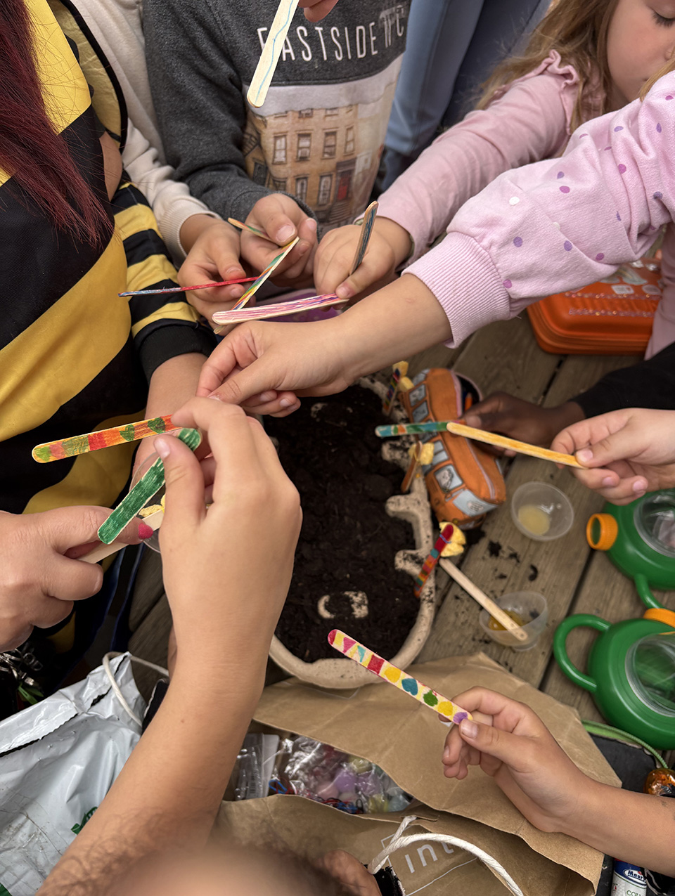 foto di bambini con palette di legno e vaso di terra