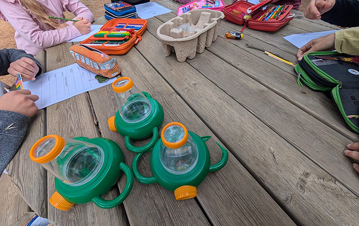foto di bambini intorno a un tavolo con fogli, astucci